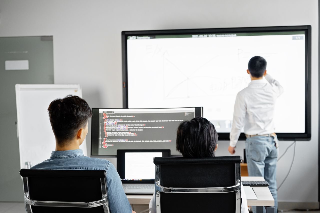 Crafting Captivating Headlines: Your awesome post title goes here Team conducting a business presentation with technology in a modern office setting.